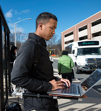 Volgenau mechanical engineering major, Marqus Keith, tries out a prototype of his invention at a bus stop on campus.
